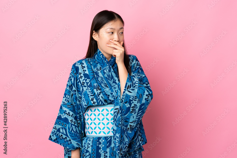 Young Chinese girl wearing kimono over isolated background doing surprise gesture while looking to the side Young Chinese girl wearing kimono over isolated background doing surprise gesture while looking to the side