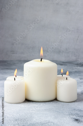 the group of white burning candles on the beton background, relaxing atmosphere