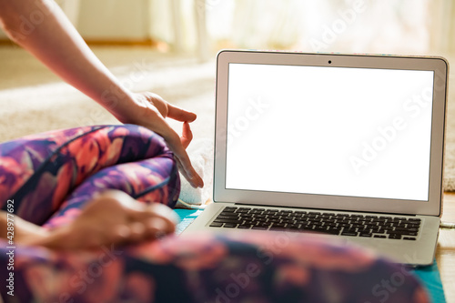 Woman using laptop and working out on yoga mat at home. Distant work. Healthy lifestyle and social media concept. White empty screen. Healthy lifestyle and social media. Close-up white empty screen. 