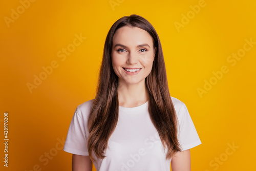 Photo of lovely cheerful lady toothy smile wear white t-shirt on yellow background © Tetiana