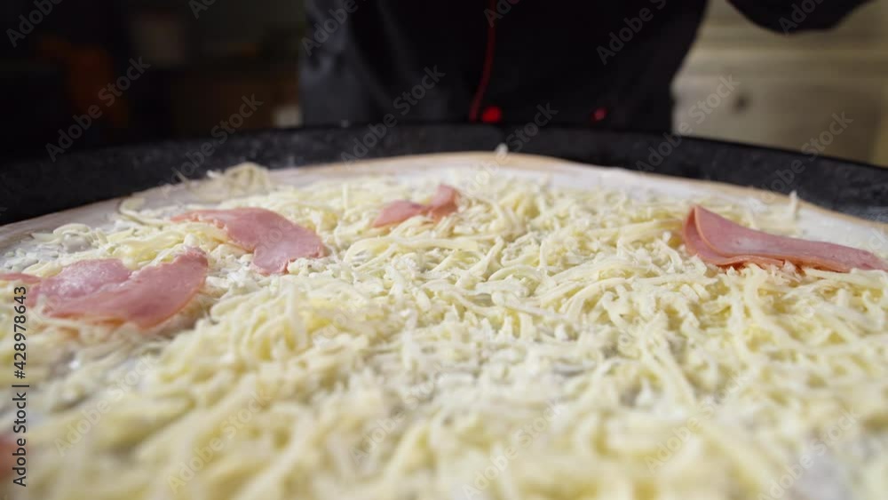 The process of making a large pizza. The hands of the chef in black