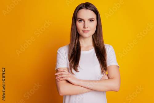 Photo of charming confident lady crossed hands wear white t-shirt posing on yellow background