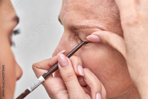 Woman at the reception at the beautician applies makeup