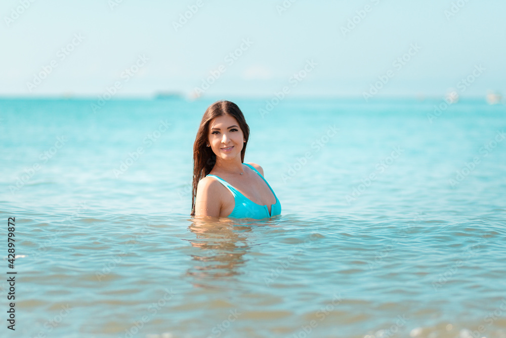 A young woman poses while swimming in the ocean. The concept of summer holidays A young woman poses while swimming in the ocean. The concept of summer holidays