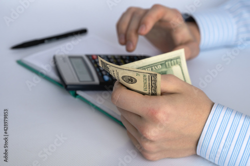 Men's hands with money, notepad, calculator and pen on a white background. Home finance. Financial accounting. Business concept. Close-up