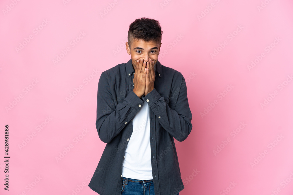 Young Brazilian man isolated on pink background happy and smiling covering mouth with hands Young Brazilian man isolated on pink background happy and smiling covering mouth with hands