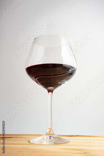 Elegant wineglass with red wine on bright vintage wooden background