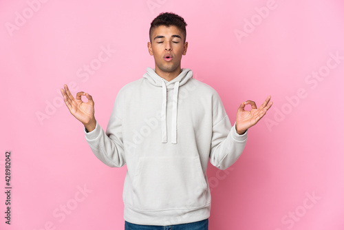 Young Brazilian man isolated on pink background in zen pose © luismolinero