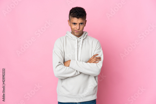 Young Brazilian man isolated on pink background feeling upset