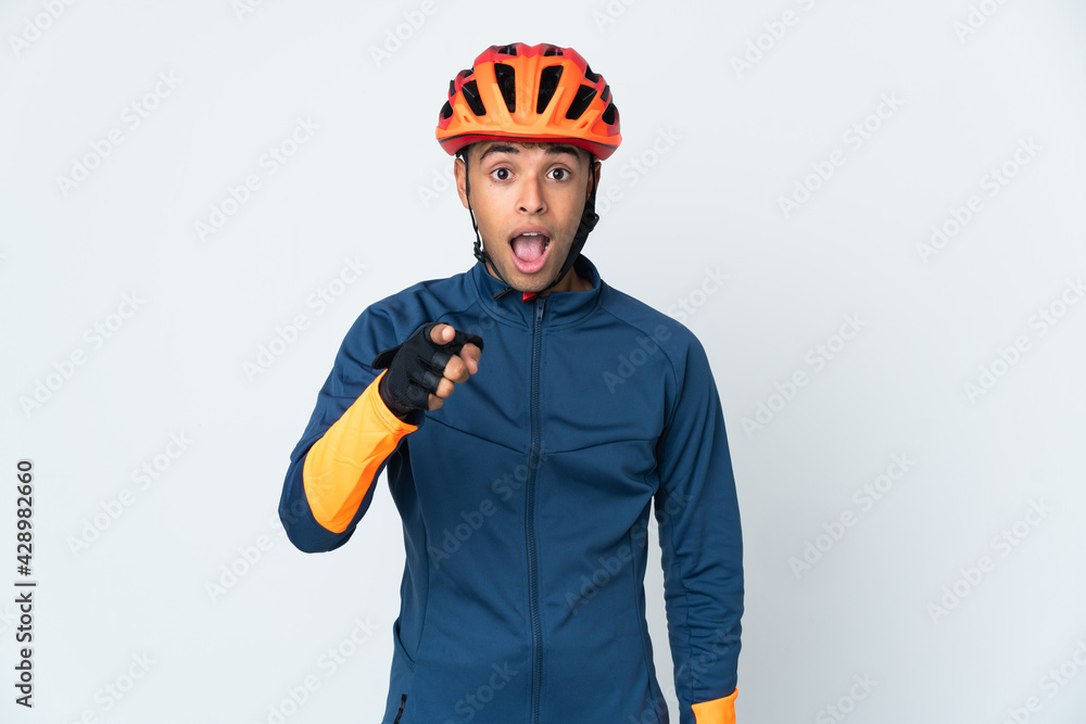 Young cyclist Brazilian man isolated on white background surprised and pointing front - obrazy, fototapety, plakaty 