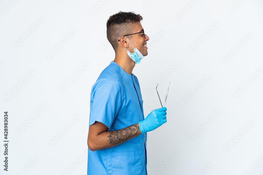 Brazilian dentist holding tool isolated on white background laughing in lateral position Brazilian dentist holding tool isolated on white background laughing in lateral position