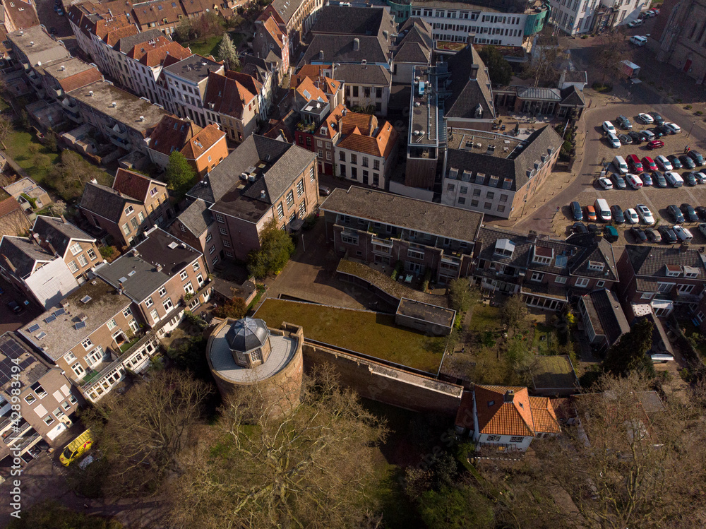Top down aerial view of historic Bourgonje stronghold tower and city wall with historic city center of Zutphen, The Netherlands, in the background