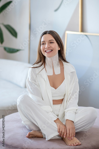 Young woman in white sitting in a room with tapes on her neck Free Download Young woman in white sitting in a room with tapes on her neck - GFXLoad