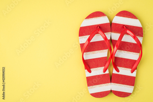 Cuadro en lienzo Top view photo of striped red and white flip-flops on isolated yellow background