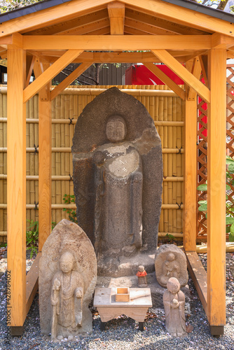 Wooden shrine dedicated to Jizo bodhisattva symbol of filial piety to protect children holding a pewter staff and wwearing a red bib in the Atago shrine of Kamiyacho. photo