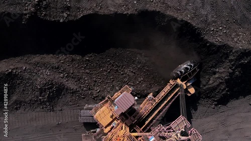 View from above. Open pit coal mining. Large mining equipment picks up coal from the warehouse with a bucket.