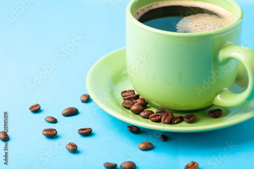 Hot fresh coffee with foam in the green cup on a color background
