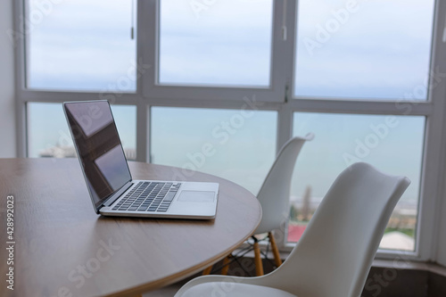 workplace, wooden table armchair laptop, sea view. © velimir