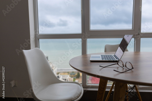 workplace, wooden table armchair laptop, sea view.