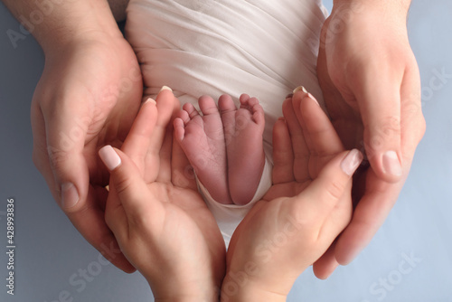 Baby feet in parent hands. Father and her child. Feet of newborn baby. Happy family and parenthood concept