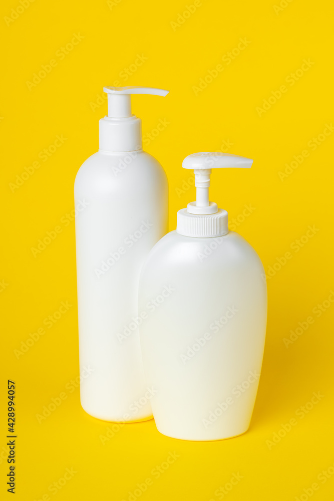 Two plastic bottles on yellow background, set of cosmetic containers with a dispenser. Toiletries, pump lotion. Moisturizing cream for body and face. Liquid soap, personal hygiene concept, cleanliness Two plastic bottles on yellow background, set of cosmetic containers with a dispenser. Toiletries, pump lotion. Moisturizing cream for body and face. Liquid soap, personal hygiene concept, cleanliness