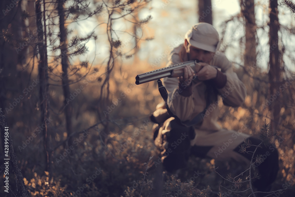 Naklejka premium hunting man / hunter with a gun hunting in the autumn forest, yellow trees landscape in the taiga