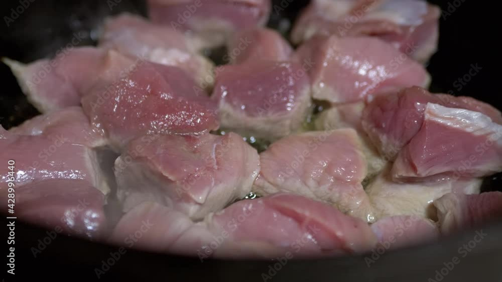 Juicy, Fresh Pieces of Pork are Fried in a Cast-iron Cauldron with Vegetable Oil. The pieces of raw meat are fried in hot oil. Cooking a delicious dinner in home kitchen, on a gas stove. 4K. Close up. Juicy, Fresh Pieces of Pork are Fried in a Cast-iron Cauldron with Vegetable Oil. The pieces of raw meat are fried in hot oil. Cooking a delicious dinner in home kitchen, on a gas stove. 4K. Close up.