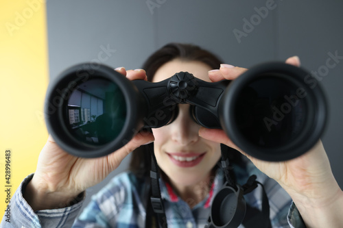 Woman looking through black binoculars and holding it with her hands