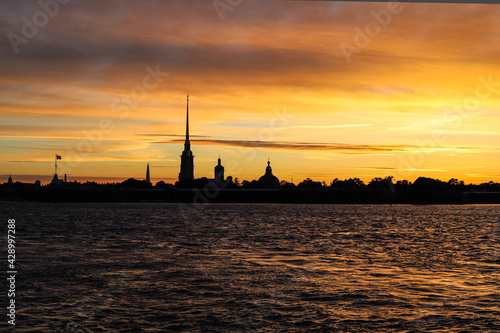 Sunset over the city on the coast. Beautiful orange sunset over the river, the silhouette of the city at sunrise over the river. Sunset over the Neva River, the silhouette of St. Petersburg.