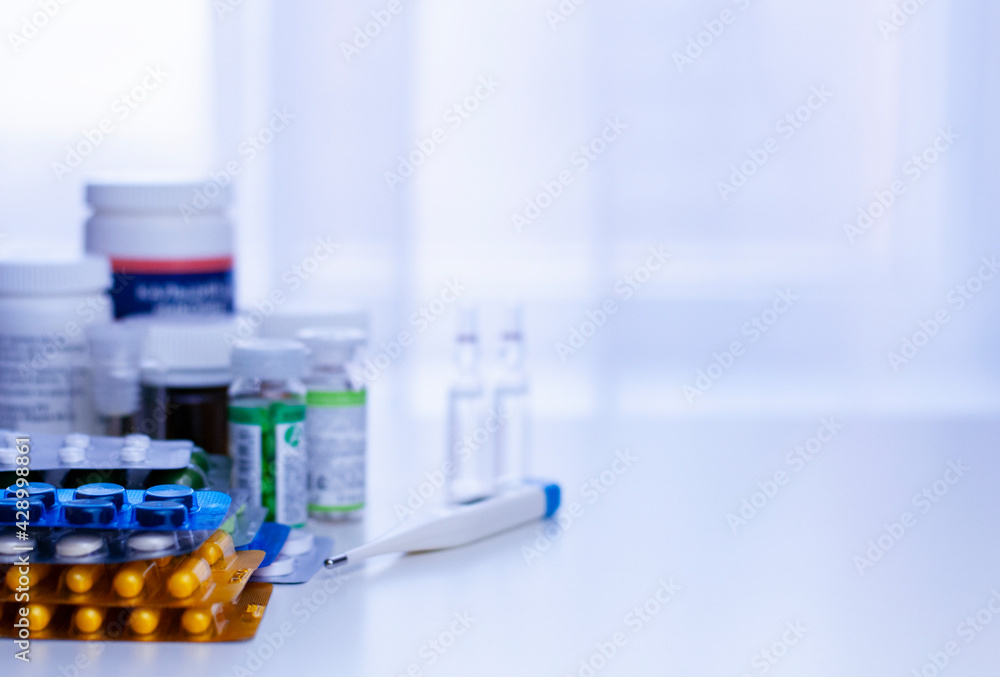 medicine background with packs of pills, glass bottle, ampoules, medical masks on the white table