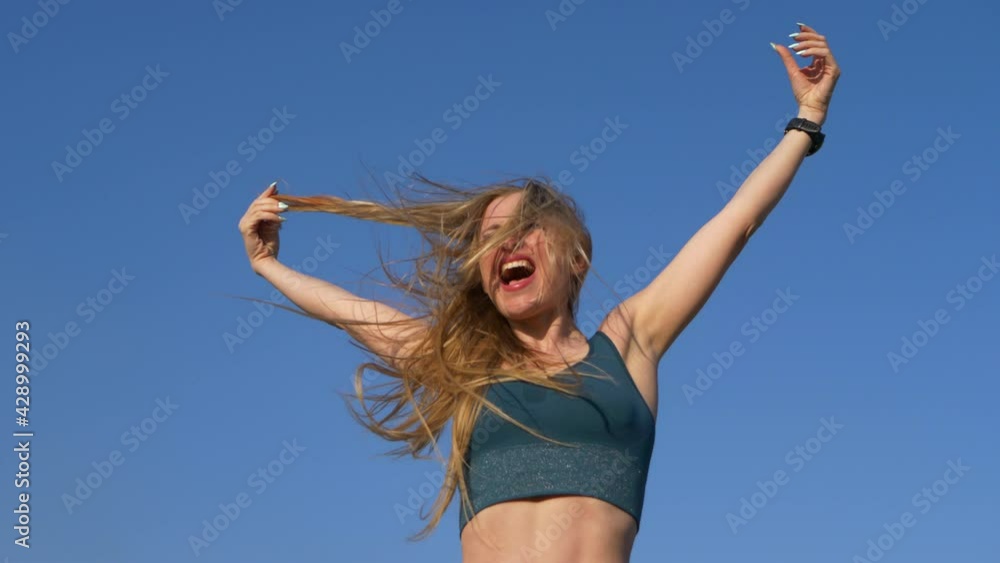 Emotional portrait of blonde caucasian girl on bright blue sky background. Concept: emotions after big victory. Wind blows white hair. Emotional portrait of blonde caucasian girl on bright blue sky background. Concept: emotions after big victory. Wind blows white hair.