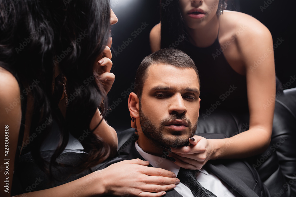 Obraz premium sensual women seducing young businessman on black background.