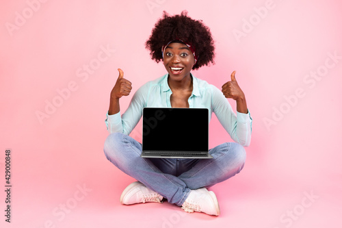 African Woman Showing Laptop Screen Sitting Gesturing Thumbs-Up, Pink Background © Prostock-studio