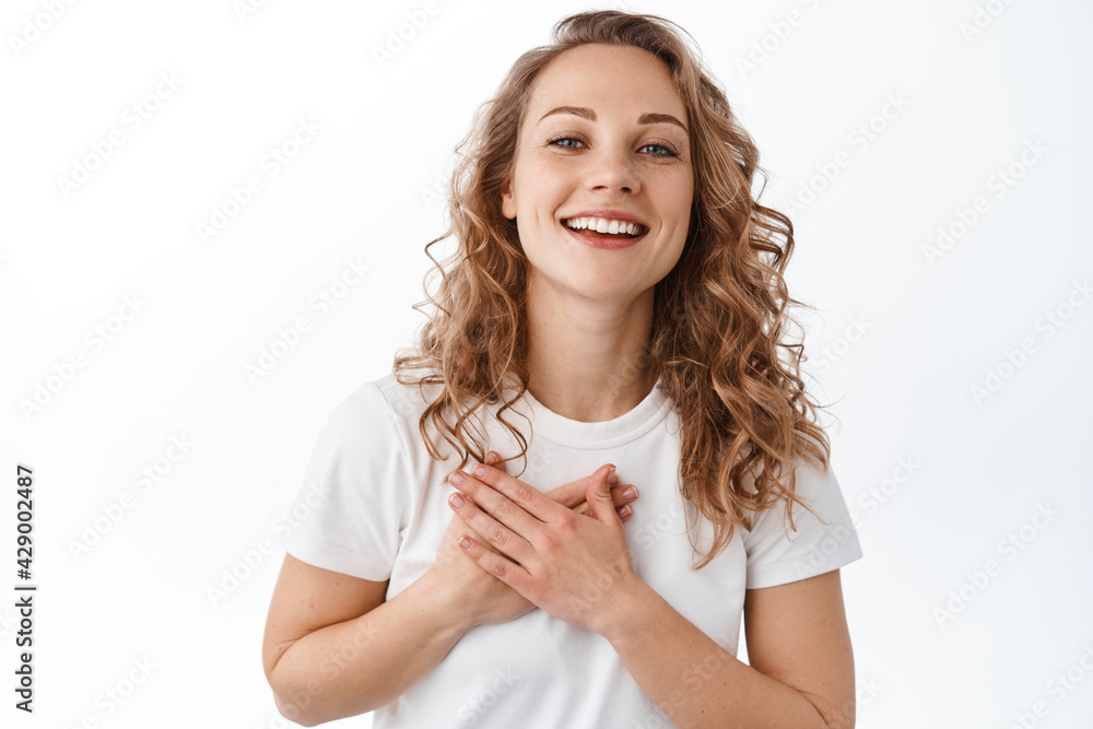 Thank you. Happy and pleased blond girl holding hands on heart and smile, express gratitude, being flattered, standing over white background Thank you. Happy and pleased blond girl holding hands on heart and smile, express gratitude, being flattered, standing over white background