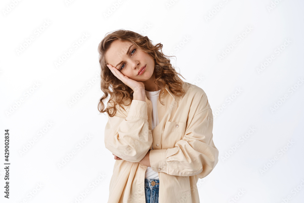 Bored and indifferent woman lean on hand and stare with bothered, annoyed face, tired of listening something lame or boring, standing over white background Bored and indifferent woman lean on hand and stare with bothered, annoyed face, tired of listening something lame or boring, standing over white background