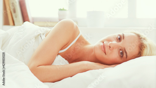 Pretty woman lying down on her bed at home