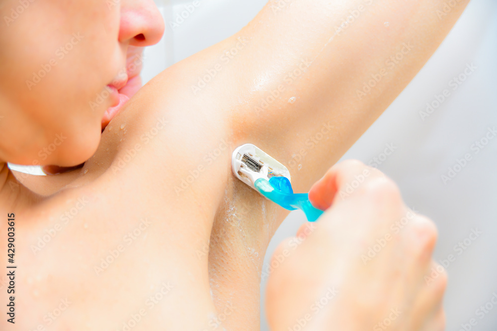 The girl in the shower shaves her armpits with a shaving machine The girl in the shower shaves her armpits with a shaving machine