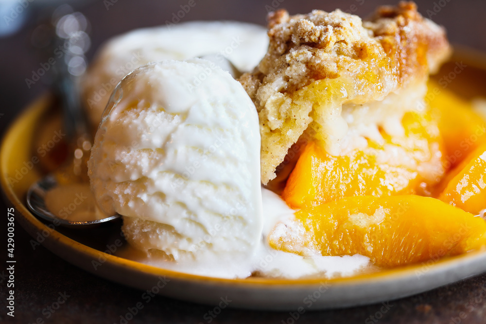 Abstract of freshly baked drop biscuit peach cobbler with melting ice cream. Selective focus with extreme blurred background. Abstract of freshly baked drop biscuit peach cobbler with melting ice cream. Selective focus with extreme blurred background.