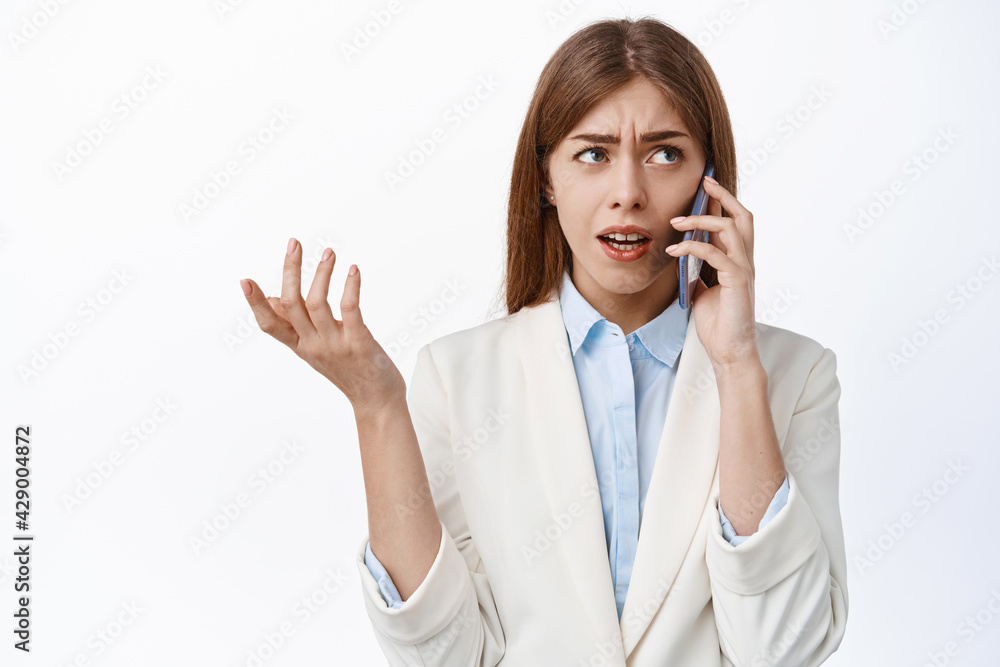 Confused corporate women talks on phone and look puzzled. Businesswoman cant understand speaker, calling someone, white background Confused corporate women talks on phone and look puzzled. Businesswoman cant understand speaker, calling someone, white background