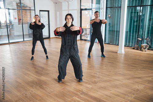 Two women and sportive man using tai chi form