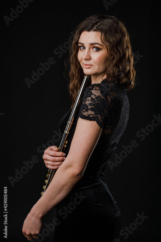 Portrait of a woman playing a transverse flute  isolated on a black background.