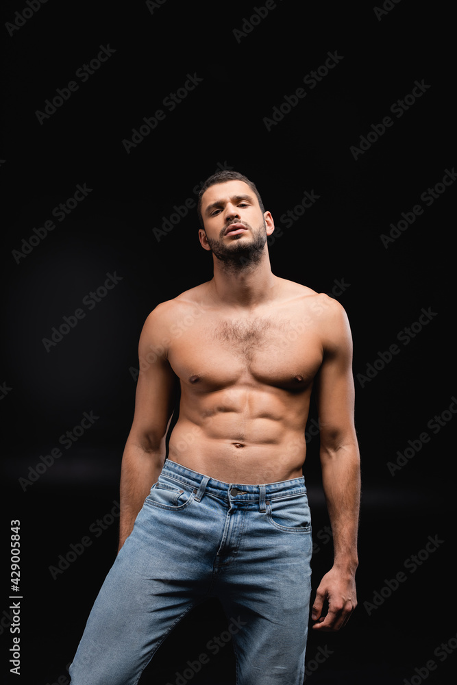Fototapeta premium sexy man with muscular torso looking at camera on black background.