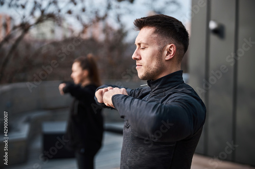 Handsome male joining fists while having tai chi training