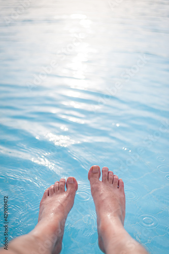 Overhead photo of feet on a background of water in swimming pool. Swimming pool, relax, health.