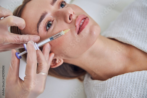 Focused elegant woman getting filler in syringe in beauty center