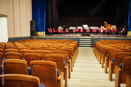 an empty concert hall with free upholstered chairs. musical instruments lie on the stage among the chairs waiting for the orchestra. no audience at the event