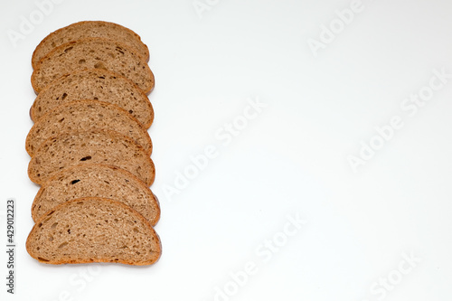 pieces of grey rye healthy bread, laid out in a row as a frame on the left on a white background