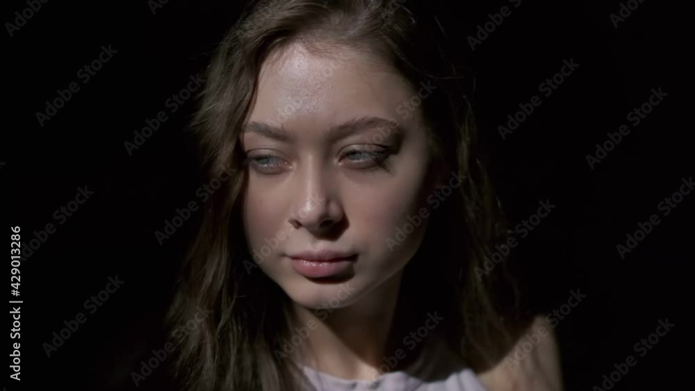 Close-up of girl with long light brown hair and grey eyes drinking coffee with pleasure from a white cup. Filmed in full face on a black background Close-up of girl with long light brown hair and grey eyes drinking coffee with pleasure from a white cup. Filmed in full face on a black background