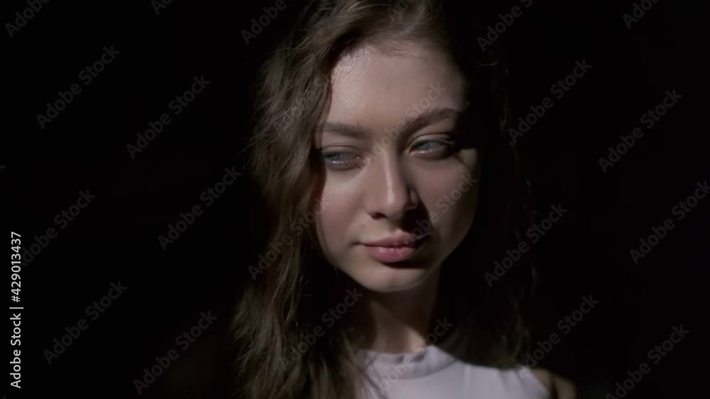 Close-up of girl with long light brown hair and grey eyes drinking coffee with pleasure from a white cup. Filmed in full face on a black background Close-up of girl with long light brown hair and grey eyes drinking coffee with pleasure from a white cup. Filmed in full face on a black background