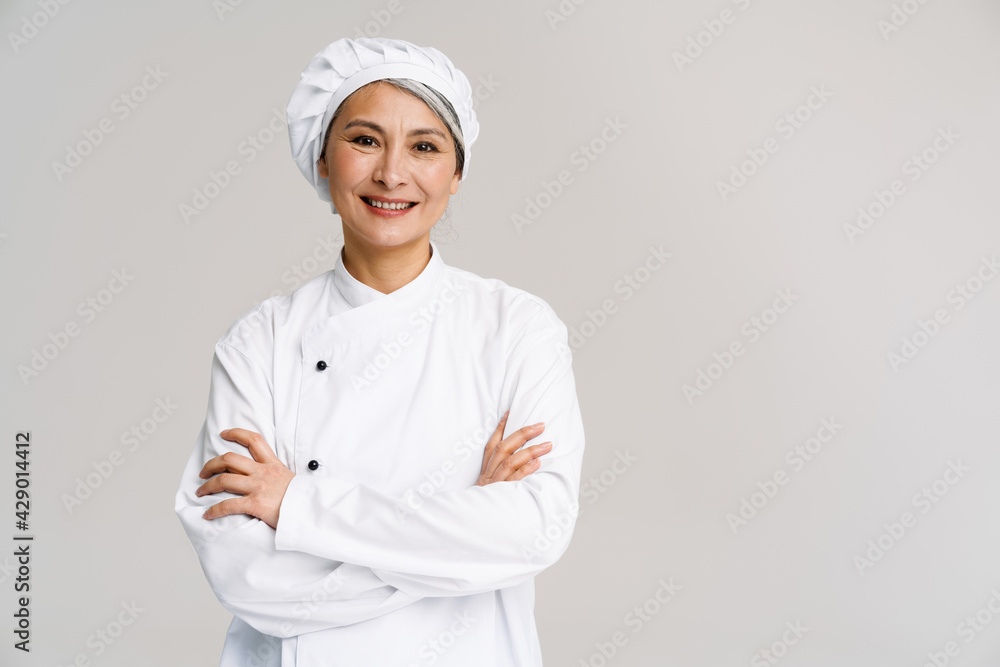 Asian mature woman in chef uniform posing with arms crossed Asian mature woman in chef uniform posing with arms crossed